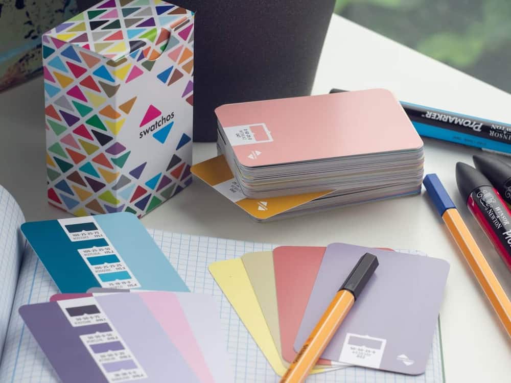 Mesa de trabajo de diseño con guías de color, rotuladores y cuaderno cuadriculado